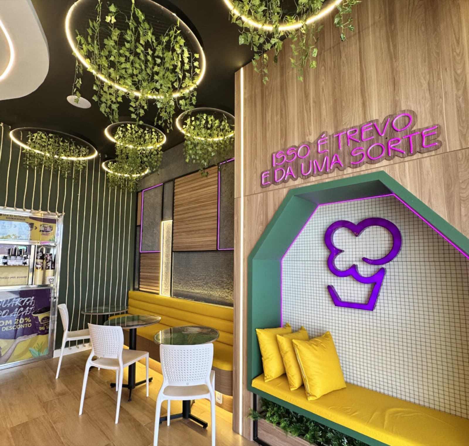 Interior de uma loja Trevo Açaí com madeira, folhagem e neon